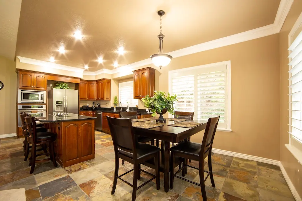 Square dining table with a vase on top placed in a dining room.