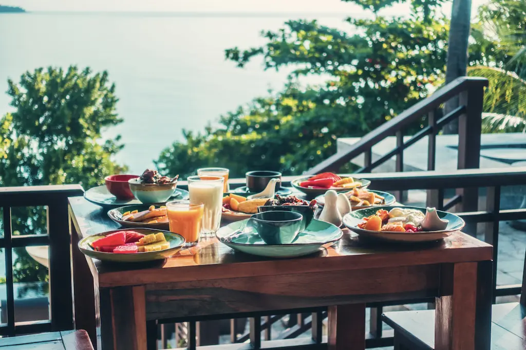 A dining table on the balcony with food and drinks.