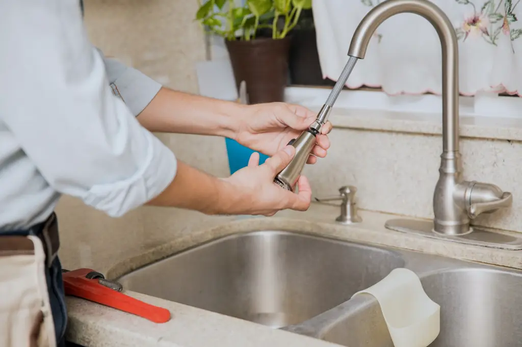 A person taking out the kitchen faucet head to clean.