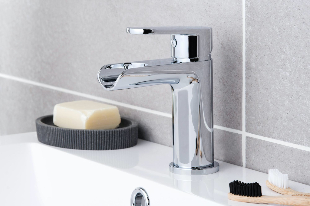 A shiny single hole faucet with a soap holder with soap next to it.