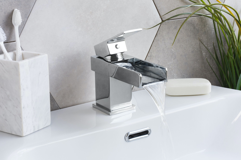 A stylish modern single hole faucet with running water.